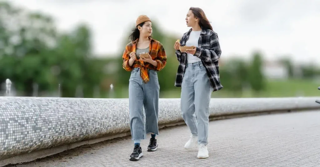 Two young women walking and smiling while enjoying the health benefits of walking every day