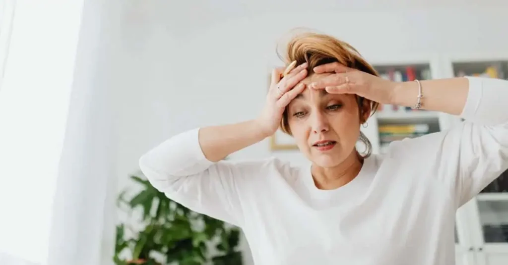 How long does menopause last? Woman holding her head with a headache symbol