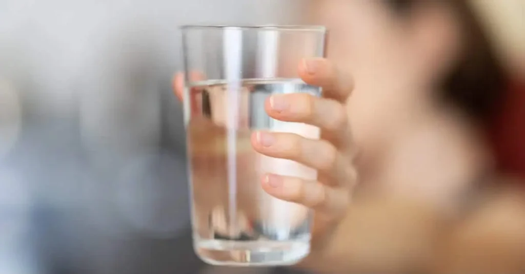 Person holding a glass of water to support healthy blood circulation