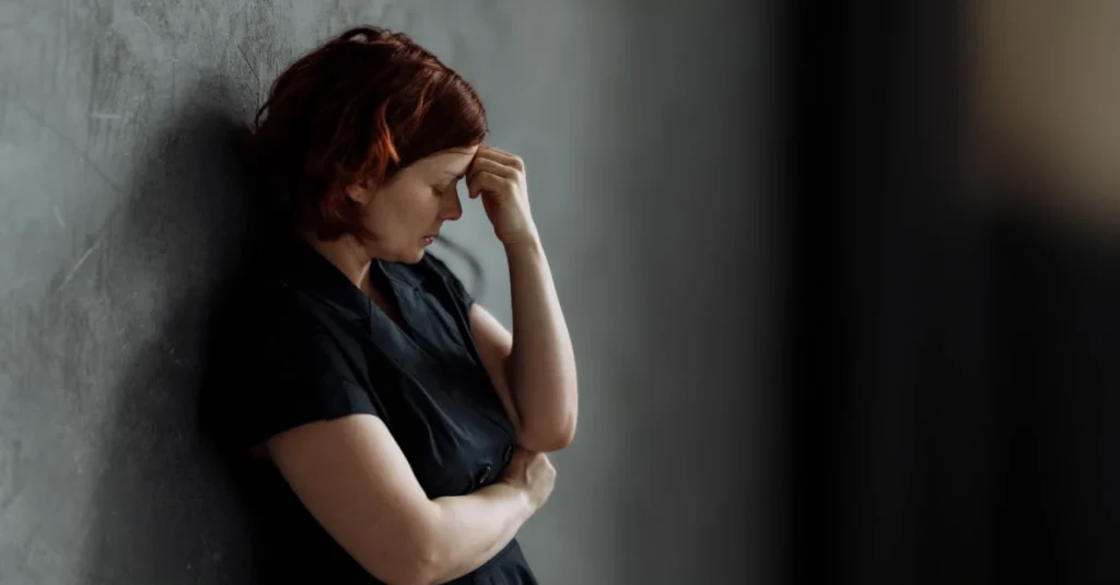 Woman standing and appearing stressed and emotionally overwhelmed