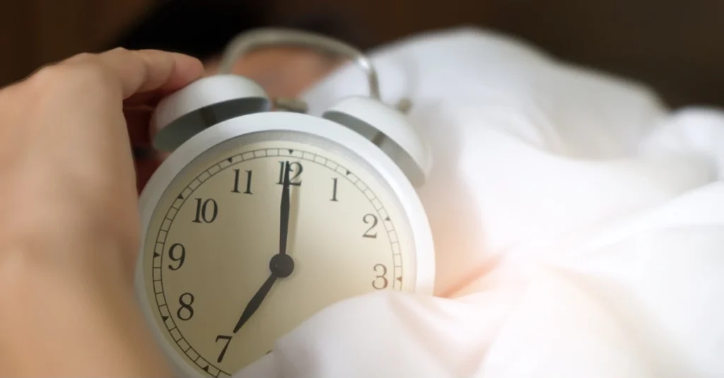 Man sleeping while holding an alarm clock