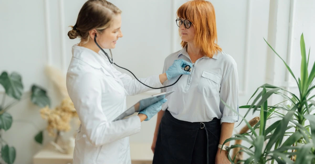 Women’s health checkup with a female doctor using a stethoscope